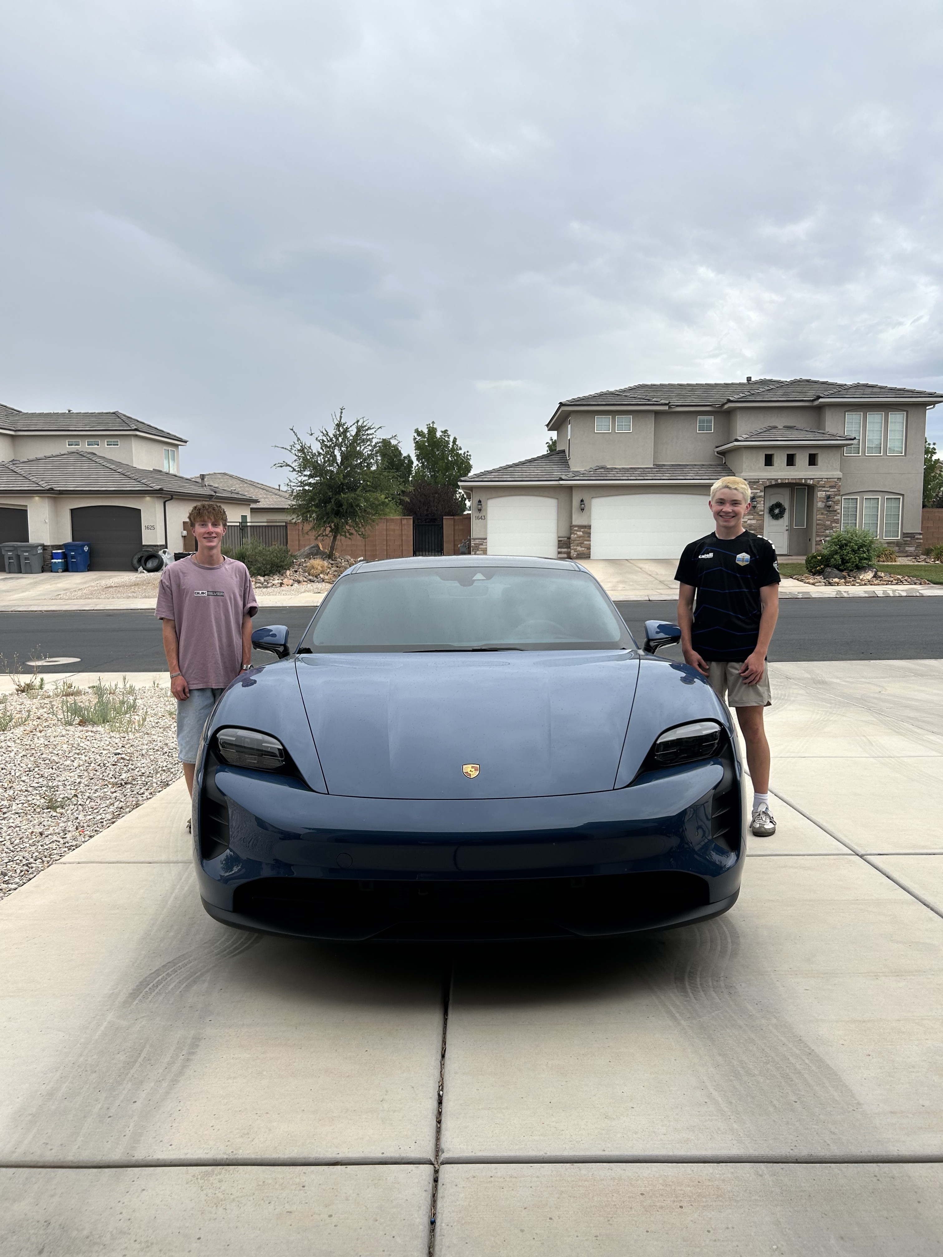 Freshly detailed blue Porsche Taycan in a Cedar City driveway